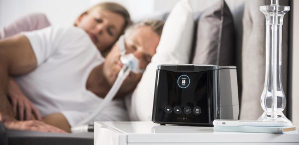 Man using CPAP machine while sleeping in bed