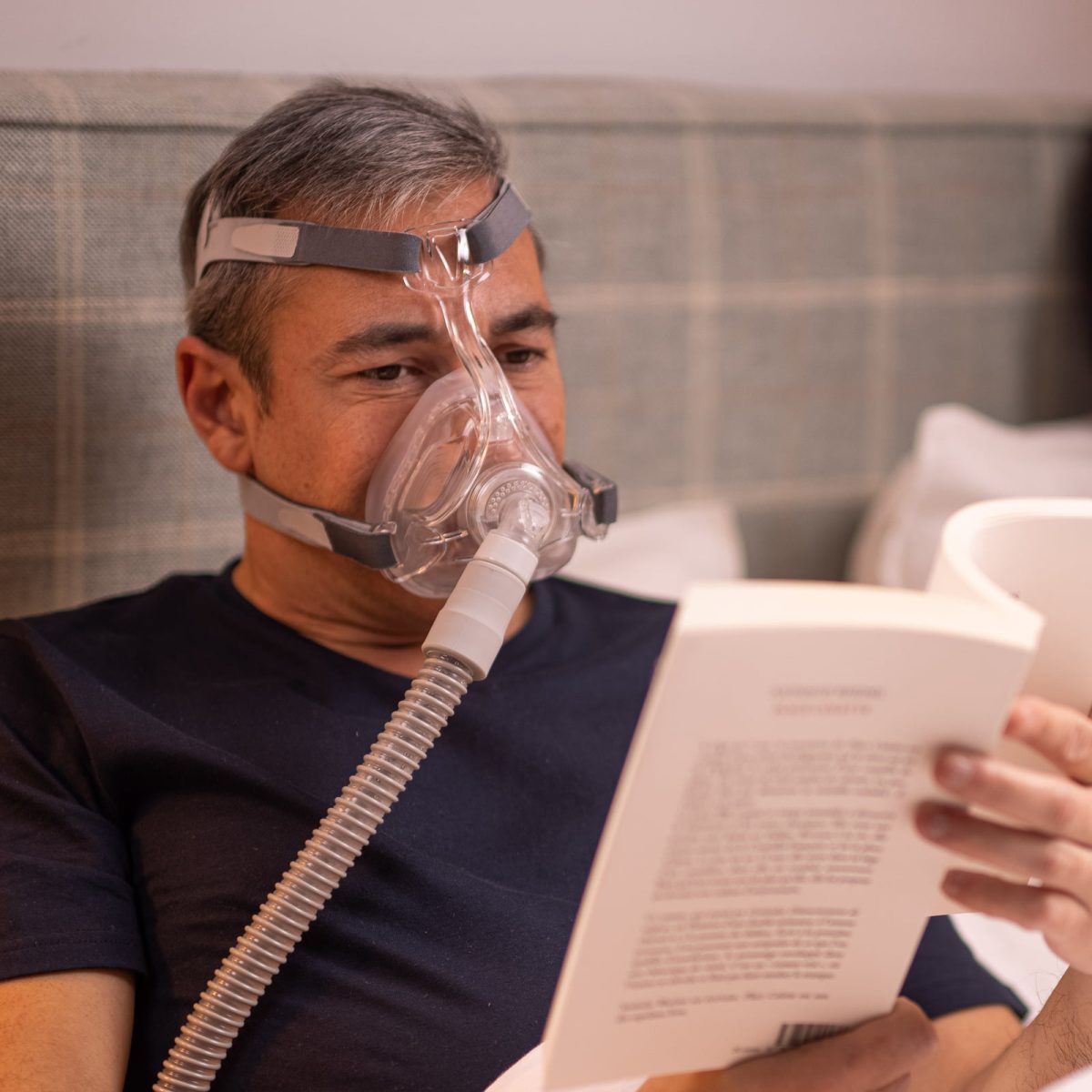 Man reading in bed using CPAP devices