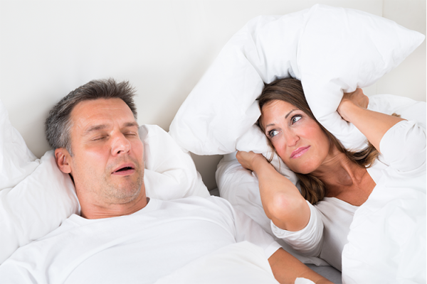 Man snoring and choking during sleep beside woman